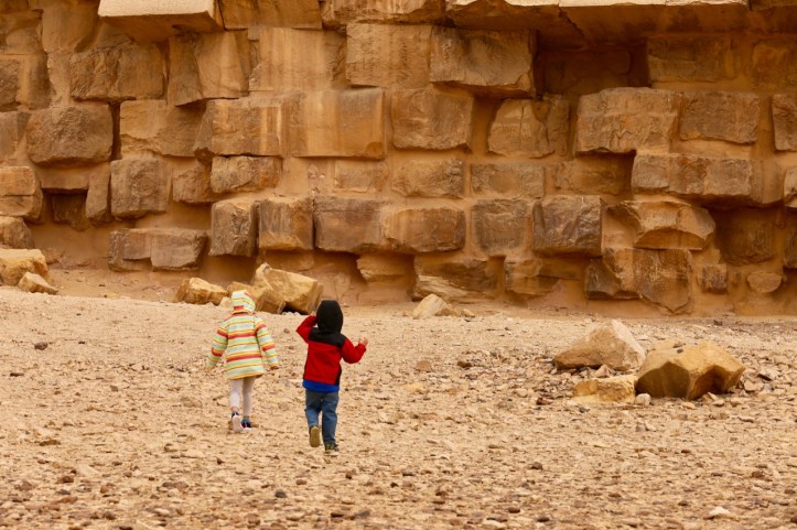 Two kids run towards the side of a pyramid